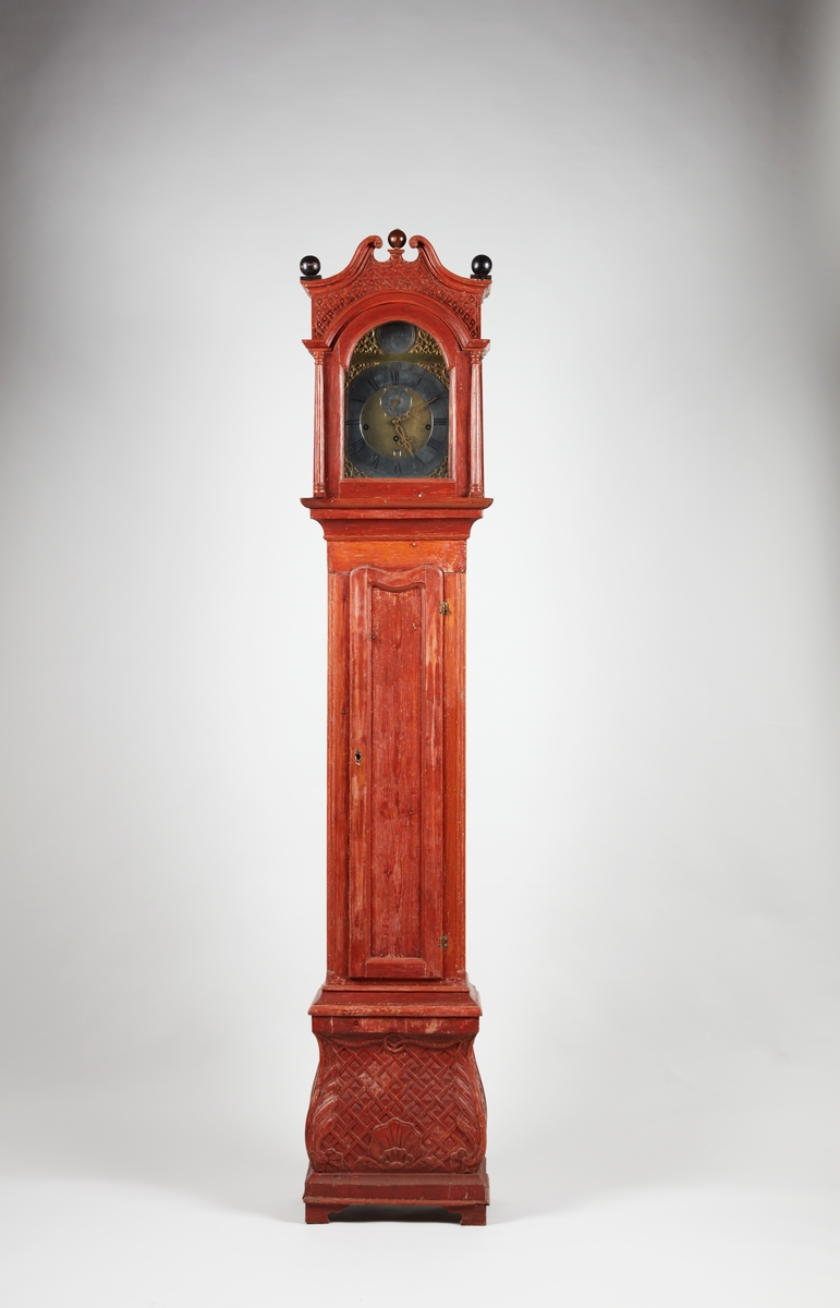 Gulvur i antatt sekundær kasse. Buet toppstykke med brutt gavl og vinduer til urverket på sidene. Rektangulær hoveddel med svungen sokkel nederst. Toppstykket dekorert med utskåret gitterverk øverst samt tre kuler på gesimsen og søyler på hver side av lysåpningen. Hoveddelen av kassen med pendeldøren er udekorert, sokkelen dekorert med utskåret gitterverk samt blader (akantus) på sidene og musling på midten nederst. Hele kassen malt ensfarget rød, kulene på gesimsen er sorte.

Urverk av messing forsynt med spillverk med elleve bjeller (visstnok til to melodier) samt én timeslagbjelle. Støpt dekor i tallskivens hjørner, hovedsakelig bladverk og c-formede ornamenter i et intrikat mønster. Midtfeltet er finhamret uten annen ornamentikk. Forsølvet timering og stjerneformet sekundring samt navneplate med signatur øverst og datoring som vises over sekstallet nederst.