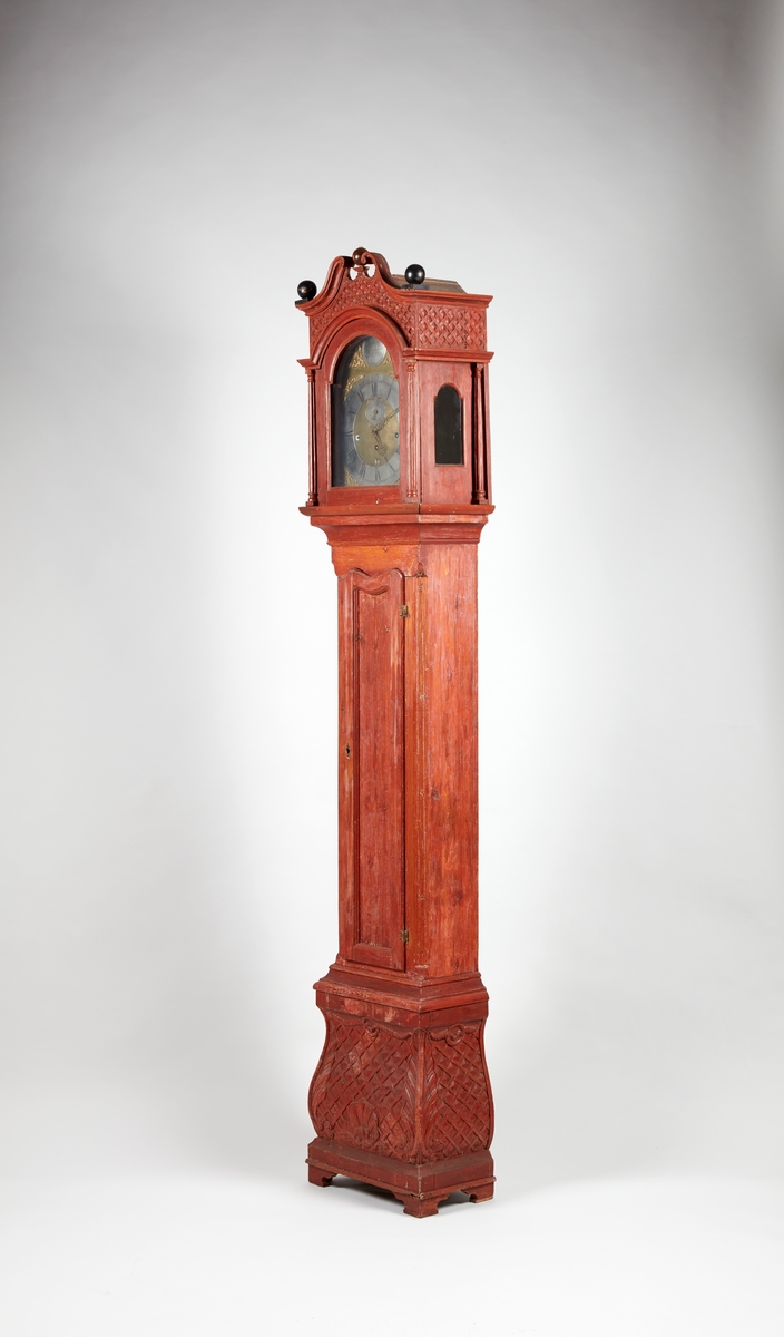 Gulvur i antatt sekundær kasse. Buet toppstykke med brutt gavl og vinduer til urverket på sidene. Rektangulær hoveddel med svungen sokkel nederst. Toppstykket dekorert med utskåret gitterverk øverst samt tre kuler på gesimsen og søyler på hver side av lysåpningen. Hoveddelen av kassen med pendeldøren er udekorert, sokkelen dekorert med utskåret gitterverk samt blader (akantus) på sidene og musling på midten nederst. Hele kassen malt ensfarget rød, kulene på gesimsen er sorte.

Urverk av messing forsynt med spillverk med elleve bjeller (visstnok til to melodier) samt én timeslagbjelle. Støpt dekor i tallskivens hjørner, hovedsakelig bladverk og c-formede ornamenter i et intrikat mønster. Midtfeltet er finhamret uten annen ornamentikk. Forsølvet timering og stjerneformet sekundring samt navneplate med signatur øverst og datoring som vises over sekstallet nederst.