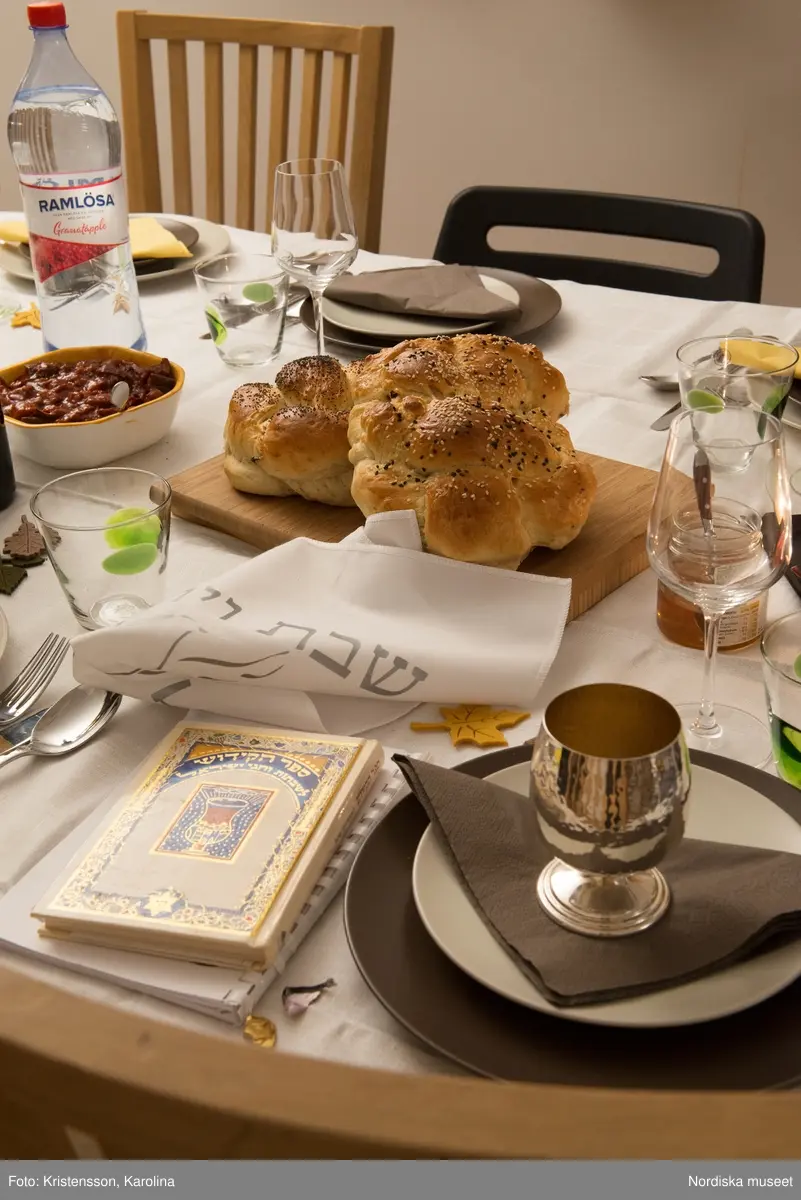 Rosh Hashana. Maten på ett judiskt nyårsbord: granatäpple, honung, bröd, äppelskivor, hummus, aubergine- och tomatröra, I köket: köttgryta (Hammin??) med sötpotatis, blomkål med citron, kycklingklubbor, ingefärssoppa, kryddris med linser och russin.