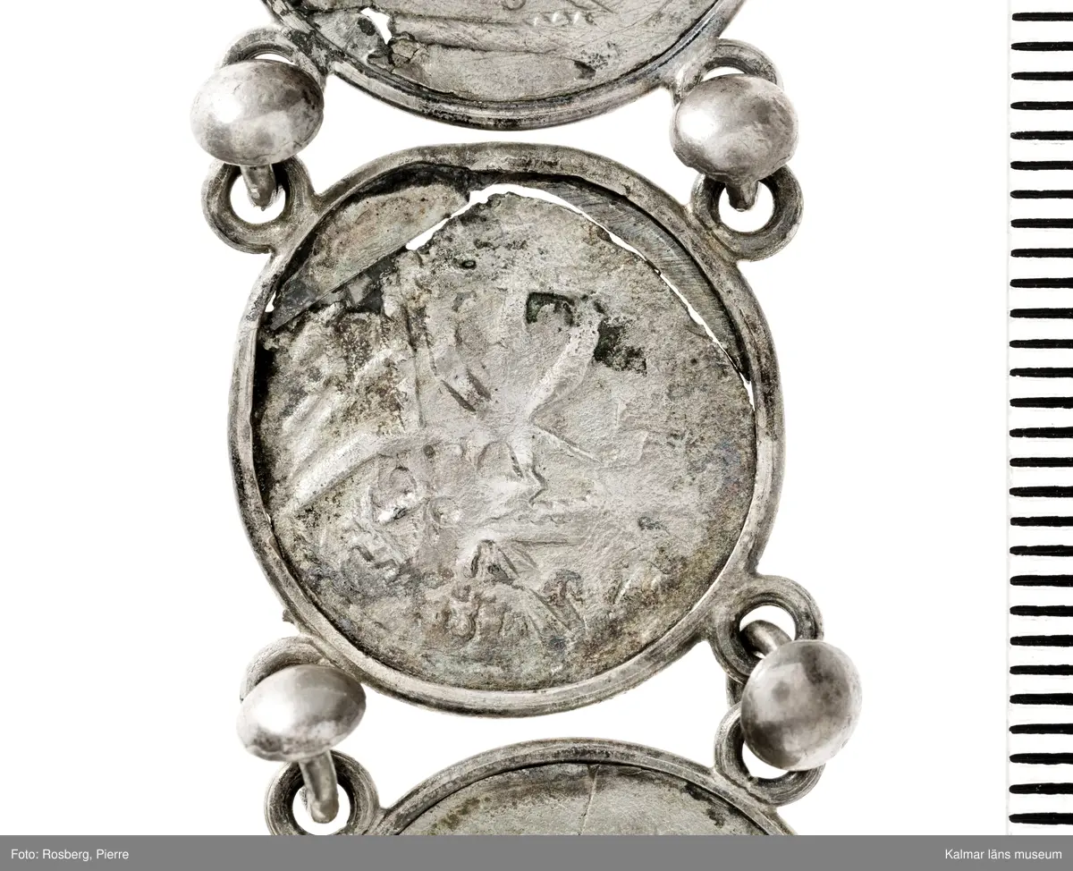 KLM 14507 Myntfynd, ett armband, bildat av silvermynt. Armbandet består av åtta infällda mynt, varav ett har lossnat från sin inramning. Mynt från Valdemar I:s tid, samt ärkebiskop Absalon, 1100-talets slut. Mynten i armbandet härstammar från ett jordfynd av ca 30 stycken likadana mynt, hittade i jorden på Åby prästgårds ägor omkr 1885. Av de nu befintliga åtta stycken, är präglade för Knut VI, Lund