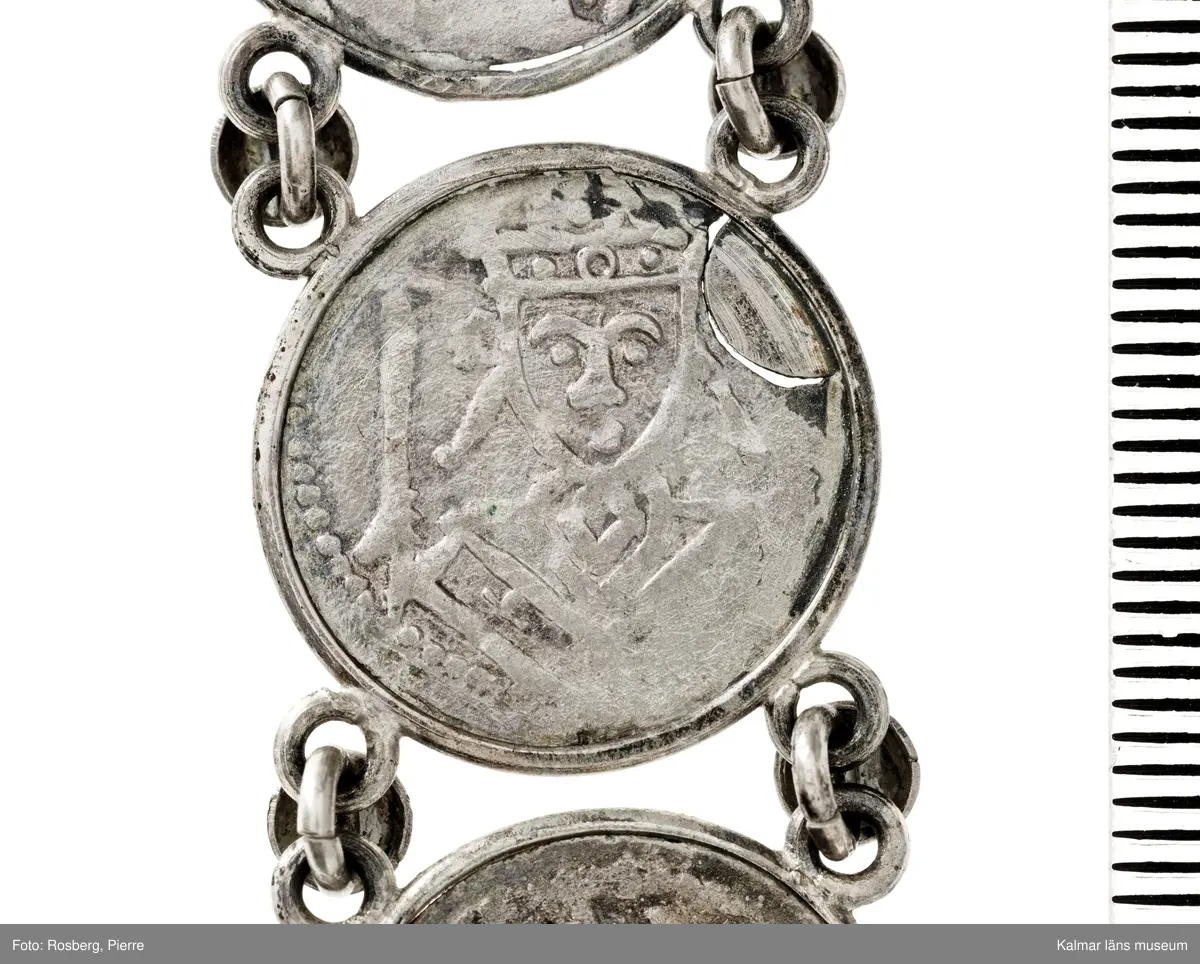 KLM 14507 Myntfynd, ett armband, bildat av silvermynt. Armbandet består av åtta infällda mynt, varav ett har lossnat från sin inramning. Mynt från Valdemar I:s tid, samt ärkebiskop Absalon, 1100-talets slut. Mynten i armbandet härstammar från ett jordfynd av ca 30 stycken likadana mynt, hittade i jorden på Åby prästgårds ägor omkr 1885. Av de nu befintliga åtta stycken, är präglade för Knut VI, Lund