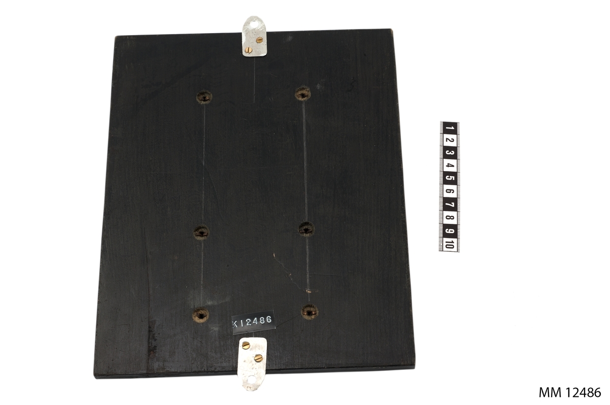 Av silver, på platta av svartpolerad ek. I relief, bild av naken yngling i strid med en eldsprutande drake, därunder följande text: Brandbolagens förtjänsttecken för berömvärt släckningsarbete. På bricka på plattan, texten: Kryssaren Tre Kronor Timber trading den 10/8, Järntorget den 25/8 och magasinkvarteret den 4/9 1947 Göteborg.