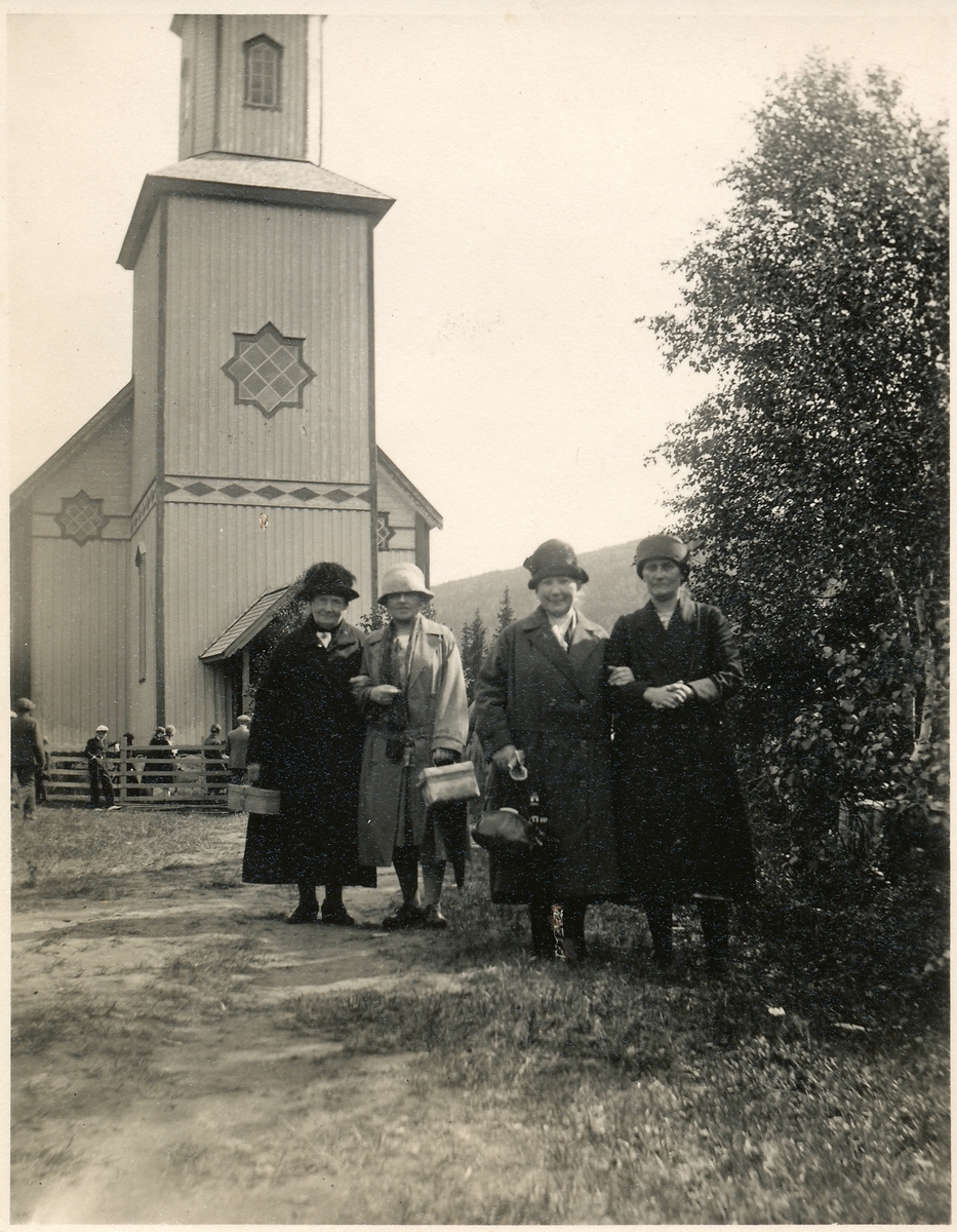 Nevernes kapell. Fire kvinner med kåpe og hatt står foran kirka.