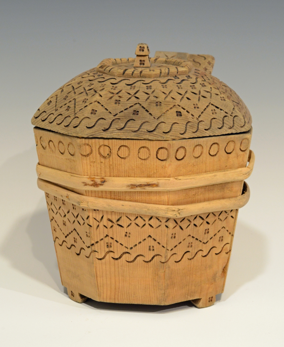 Fra katalog: Ottekantet smørkande og stav med hank og laak og tre smaa føtter, utvendig svimerket og en slynget ring oppe paa laaket, indvendig
rik rosette. Under staar brændemerket: A OSS 1823,