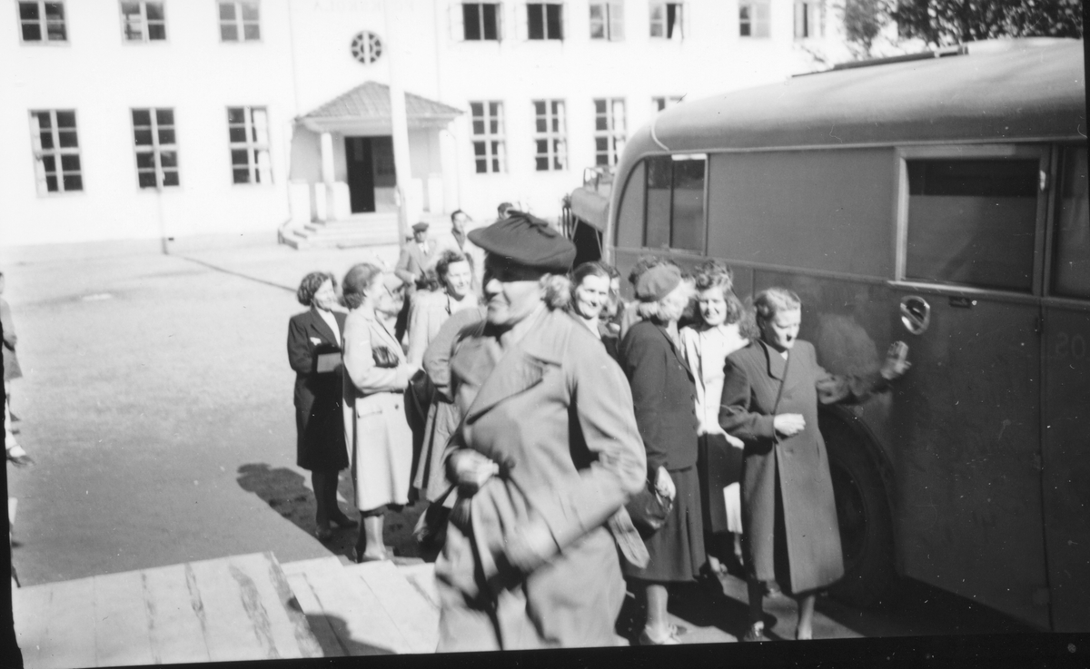 Grupp kvinnor framför buss och Södra skolan, Edsbyn.