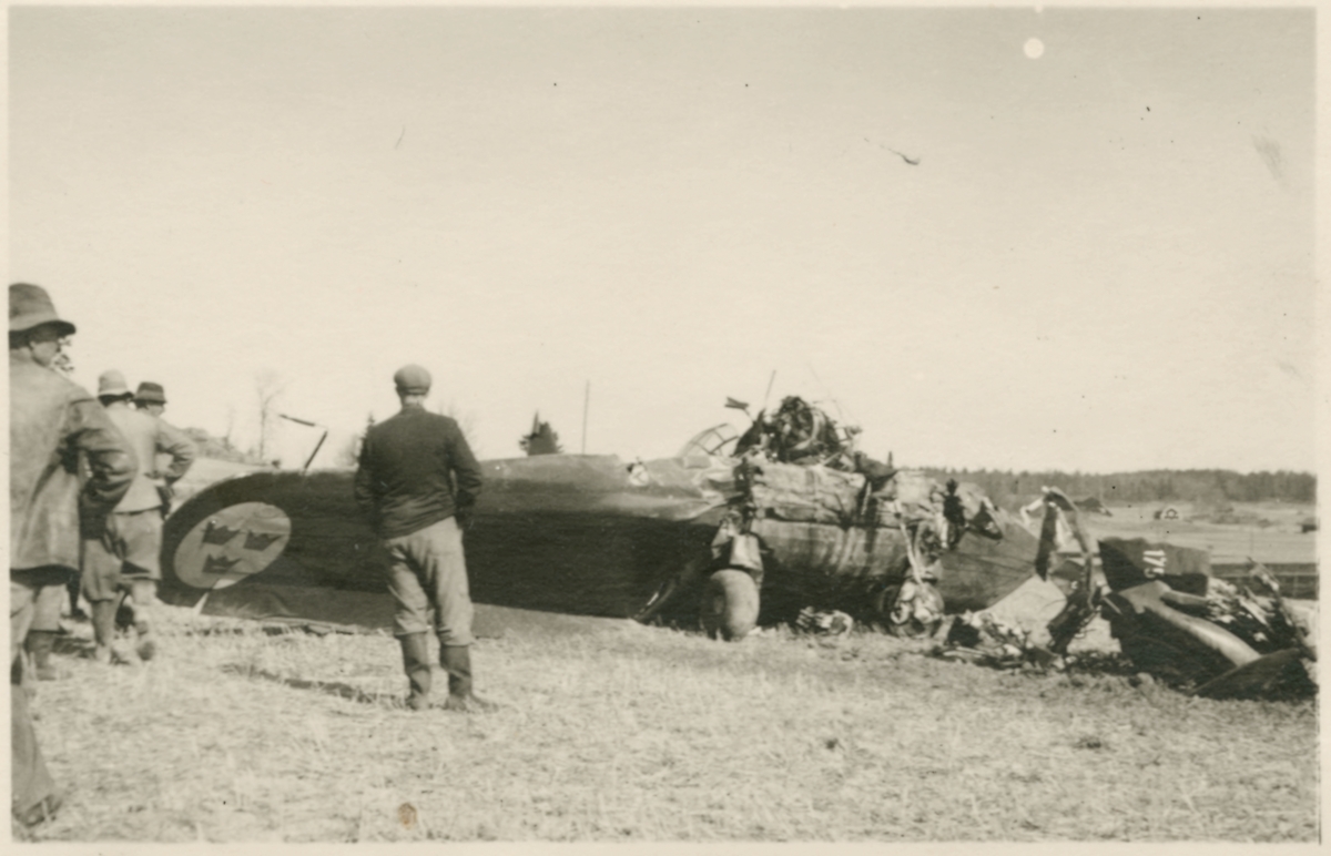 Havererat militärt skolflygplan SK 14 nummer 675, märkt F 5-175 på ett fält utanför Vittsäter, sydost om Nykil i Östergötland, den 30 april 1940. Män i närheten av flygplanet. Serie om 8 bilder.