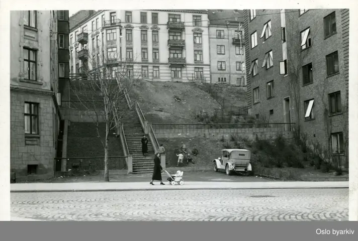 Trapp ved Waldemar Thranes gate 46 oppp til Fougstads gate.Trappen er en del av Brandts gate som starter i Geitmyrsveien og går til Bjerregaards gate.Her ved trappen lå unnarennet til Premiebakken. Dame med barnevogn. Barn i lek. Bil på parkeringsplass.