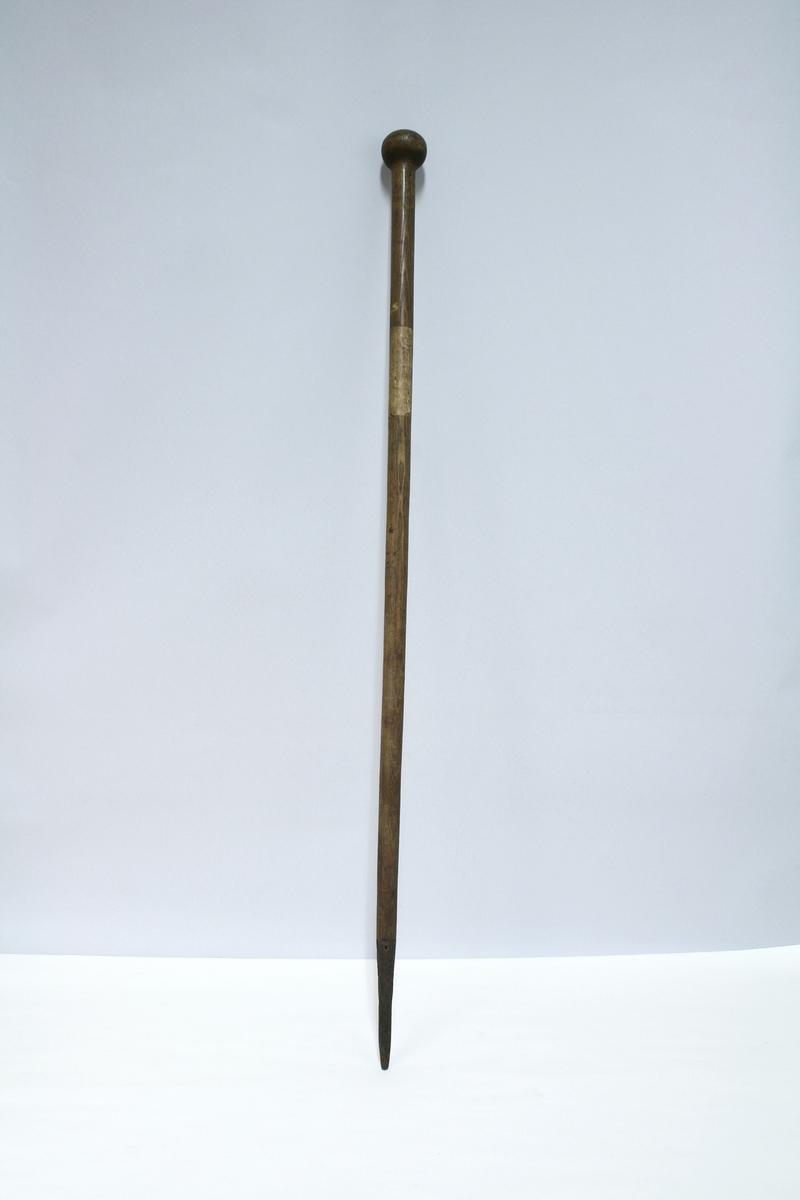 Trestav med kule i enden. Staven smalner nedover og ender i en spiss doppsko i jern.