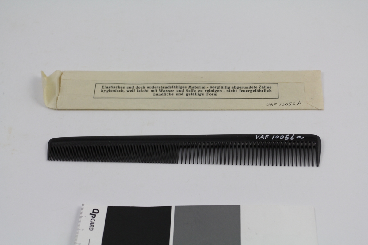 Kam (a) i original papirpose (b). Den ene halvparten fintannet, den andre grovere. Smalner litt mot den fintannede delen. Papirpose av ett stykke papir, med trykket tekst (se foto), åpning i den ene kortsiden.