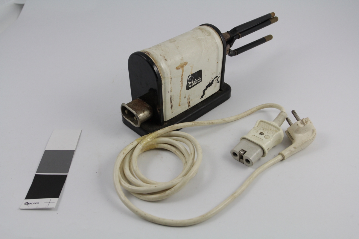 Eletrisk krølltang bestående av fire deler:
a-b) krølltenger: 2 stk. sylindriske håndtak (a kan beveges).  Når håndtakene føres sammen, presses sylinder i andre enden ned i hul del. 
c) elektrisk varmeapparat, uttak støpsel og ledning på den ene siden. Rektangulær sokkel. Påsatt rektangulær del med avrundet overside. Kortside: inntak for to krølltenger. Oval åpning. 
d) Ledning med kontakter.