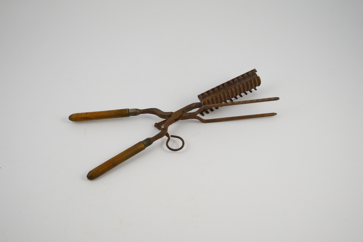 Krølltang: To jern som krysser hverandre i et hengslingsparti, og hvor den ene stang er stukket gjennom den andre. Sammenhengslingen er klinket. Det ene "jern" har to runde tynne tinder stående i spiss u-form og med butte ender. Det andre "jern" består av to deler, en fast og en bevegelig. Den flat utformede og avkuttede "arm" er festet med to nagler til et krumbøyd stykke lettmetall med 12 rett oppstående tagger på hver side. På oversiden av det krumbøyde lettmetall er lagt et 3 cm bredt rektangulært stykke lettmetall med tversgående rifler. Det riflete lettmetallstykket er bevegelig innenfor et rektangulært felt (hull), på undersiden av det andre lettmetallstykket, og hvor det er naglet fast til en bevegelig "arm". Denne "arm" består av to sammen-naglete deler stående vinkelrett på hverandre, den korte del avsluttes med en bøyd krok for fingergrep. Håndtakene dreiet med avrundet spiss i den ene enden, to metallringer markerer overgangen til jernene.