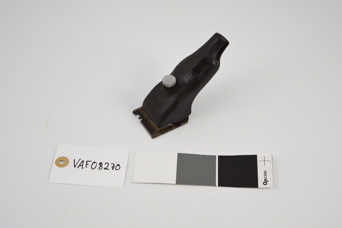 Form: Rektangulært metallbrett ("kniv") med pigger i den ene enden, spor langs undersiden. Mellom denne og maskindel et annet brett ("kniv") med pigger. Når apparatet slås på, beveger denne seg. Apparatet står skrått på kniven. Avrundede, ujevne former. Sirkulær skrue overside. Uttak (ledning) i ender.