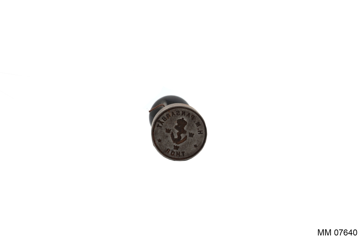 Sigill av stål med handtag av trä. Stansen cylindrisk med svarvat och svartlackerat handtag. Ingravering: H.M. Pansarbåt Thor samt ankare med kunglig krona, omgivet av tre mindre kronor. Det hela inom ring.
