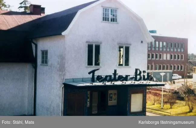 Karlsborg, teaterbio. Fotot är taget från en balkong vid Kungsgatan i början av 1970-talet. I bakgrunden syns en del av kommunalhuset. Byggnaden revs sommaren 1998. Foto: Mats (Olsson) Ståhl. Gåva av Karin Zeidlitz-Andersson. Neg finns.