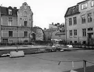 Motiv från obebyggd del av kvarteret Eolus i Linköping 1975. Till vänster ses det vackra stenhuset på adressen Läroverksgatan 4, som bland annat dekorerats med en målad fris i så kallad sgraffitoteknik. I fonden skymtar den medeltida Stenhusgården.