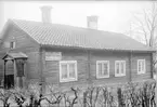 Ågatan 53 i Linköping. På husgaveln skyltar tapetserare Edvin Lundin till sin verkstad in på gården. Vy från gatan. Dokumenterad av Östergötlands museum inför rivning 1927.