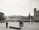 Flagghalning på Stortorget med marinen. Sjöbefäl gör honör framför stor publik och matroser.