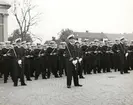 Militärer uppställda i uniform framför Tyska kyrkan på Karlskronas torg. Sjöbefälen står med värjor längst fram.