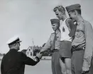 Konteramiral Johan Erik Samuelson tar en yngre, uniformsklädd man i handen under en prisutdelning. Bredvid den yngre mannen står ytterligare två yngre män, en klädd i idrottskläder och en i uniform. Bild från Marinmästerskapet i allmän idrott.