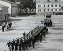 Parad med värnpliktiga på sparres kaserngård. Till vänster i bild syns högre militära tjänstemän och befäl som står omkring och på ett podium.