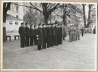 Uniformsklädda militärer av högre rang, bland annat en vice amiral, står uppställda på Sparres kaserngård. I bakgrunden syns kasern Sparre.