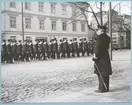 Konteramiral Samuelson står utanför Bataljon Sparre och gör honnör åt en förbiparaderande grupp med flottister på Drottninggatan. Fotot är daterat till 17-3-52.