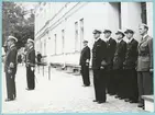 Uppställning av militärer framför Bataljon Sparre mot Drottninggatan. Främst står konteramiral Samuelson och gör honnör.
