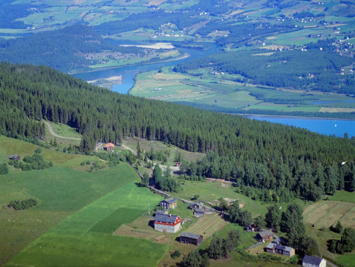 Sør-Fron, Hundorp vestside. Gården er Tofthaugen og småbruket nederst til høyre er Hyggen. Kulturlandskap. Lite, brunt hus med rødt tak i skogkanten. Gudbrandsdalslågen i bakgrunnen.