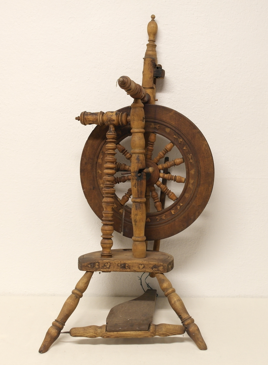 Stående hjulrokk i tre med spinneapparatet plassert over hjulet. Rokken har opprinnelig hatt tre bein.