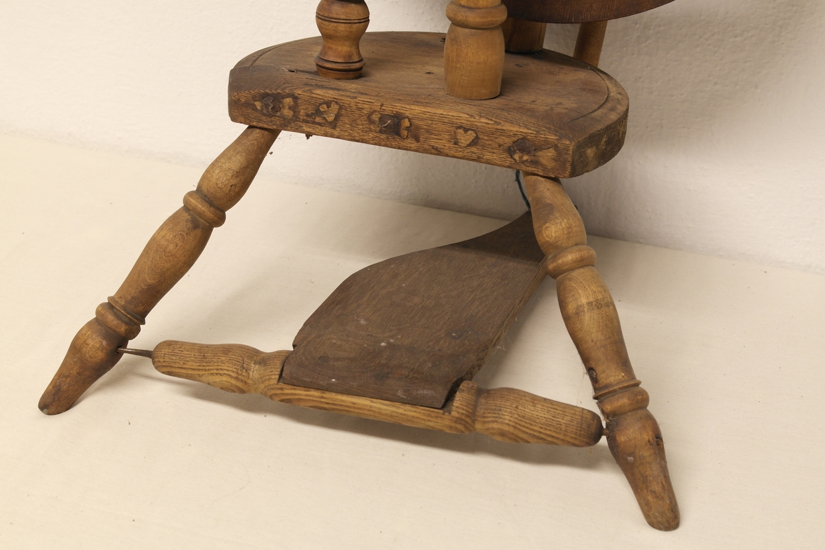 Stående hjulrokk i tre med spinneapparatet plassert over hjulet. Rokken har opprinnelig hatt tre bein.