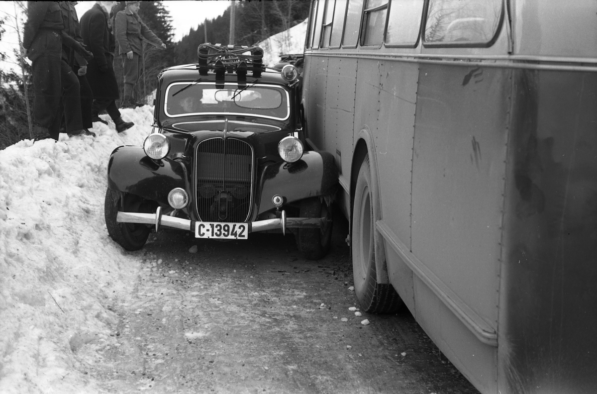 Møteuhell mellom buss og personbil på en trang Rv. 33 ytterst i Totenvika en vinterdag 1950. Bussen er "Eidsvollruta", bussen som gikk mellom Skreia og Eidsvoll. Serie på ni bilder.