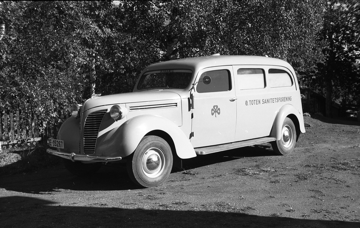Ambulanse, muligens den første anskaffet av Østre Toten Sanitetsforening. Serie på 12 bilder fra september 1948. Kvinnen på bilde nr. åtte er Gjertrud Solem som trolig er sanitetsforeningens representant, mens mannen på bilde nr. sju, og som nok er sjåføren, er Anders Skolby fra Kapp. Han ble senere sjåfør for kronsprins Olav på Skaugum, og etter det privatsjåfør for Anders Jahre .