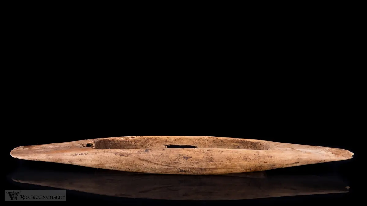 Oval med et oval hull i midtten. Avlangt spor på siden.