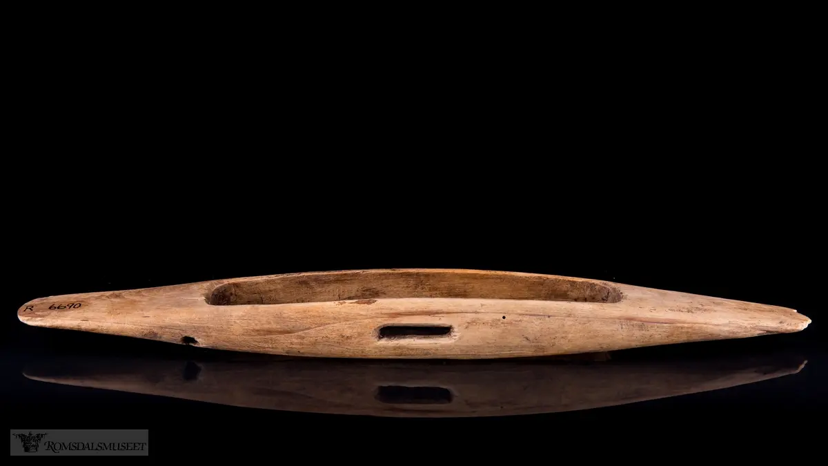 Oval med et oval hull i midtten. Avlangt spor på siden.