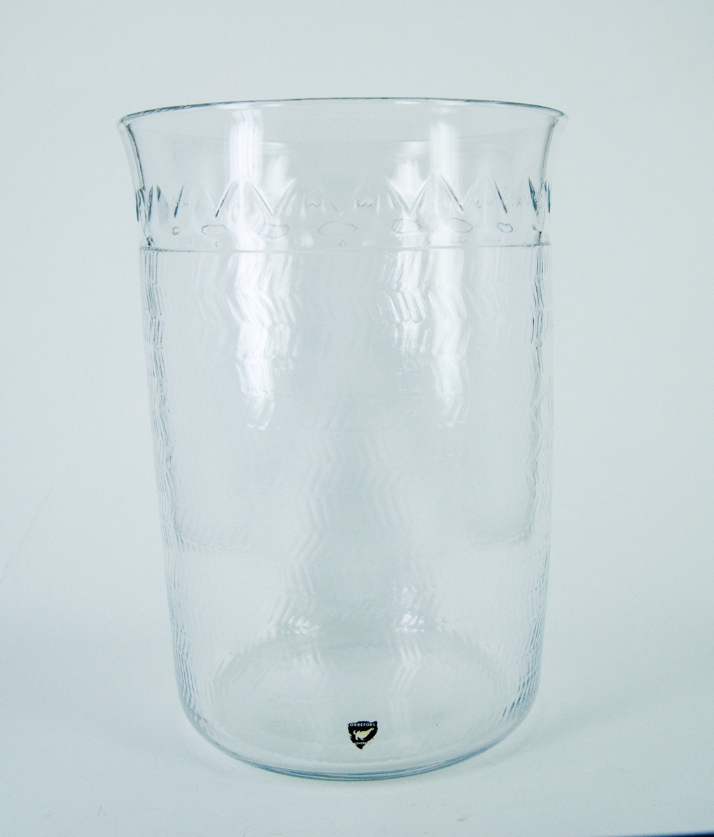 Vas i kristall. Orrefors glasbruk, design Gunnar Cyrén. Närmast cylindrisk, överst något utsvängd. Blank gravyr, fiskbensmönster. Märkt under: Orrefors Cyrén Expo 49-60 P.