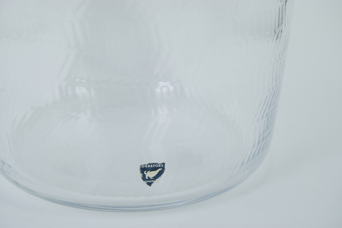 Vas i kristall. Orrefors glasbruk, design Gunnar Cyrén. Närmast cylindrisk, överst något utsvängd. Blank gravyr, fiskbensmönster. Märkt under: Orrefors Cyrén Expo 49-60 P.