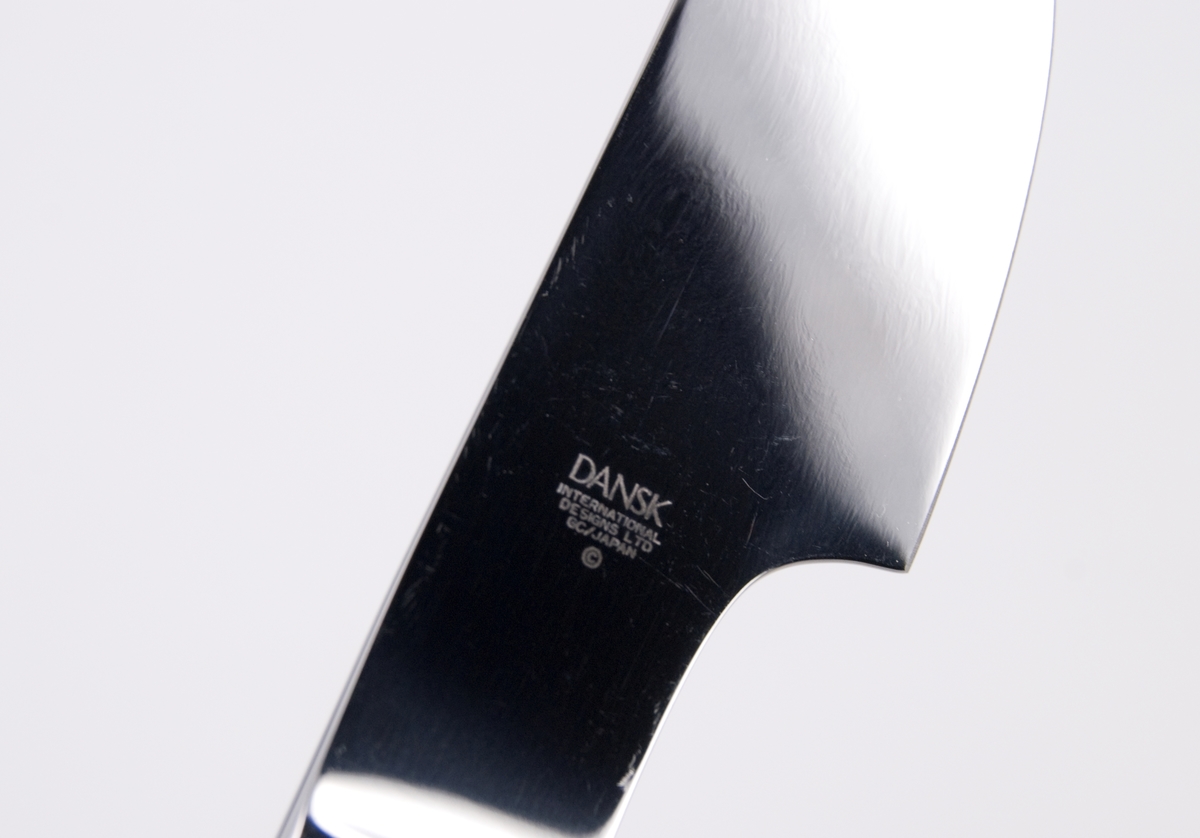 Kniv i rostfritt stål. Blad med rak ovansida och svängd egg. Slätt jämntjockt skaft med rundad ände. Märkt på bladet: DANSK INTERNATIONAL DESIGNS LTD  GC/JAPAN
Tillverkad i Japan för Dansk Designs Ltd, USA. Design Gunnar Cyrén.