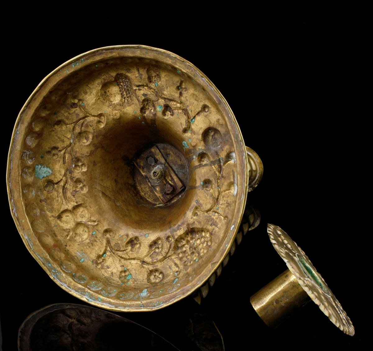 Barockljusstake av mässing, med rund fot och spiralvridet skaft. 
Foten är något kupad samt dekorerad med uthamrade växtornament.