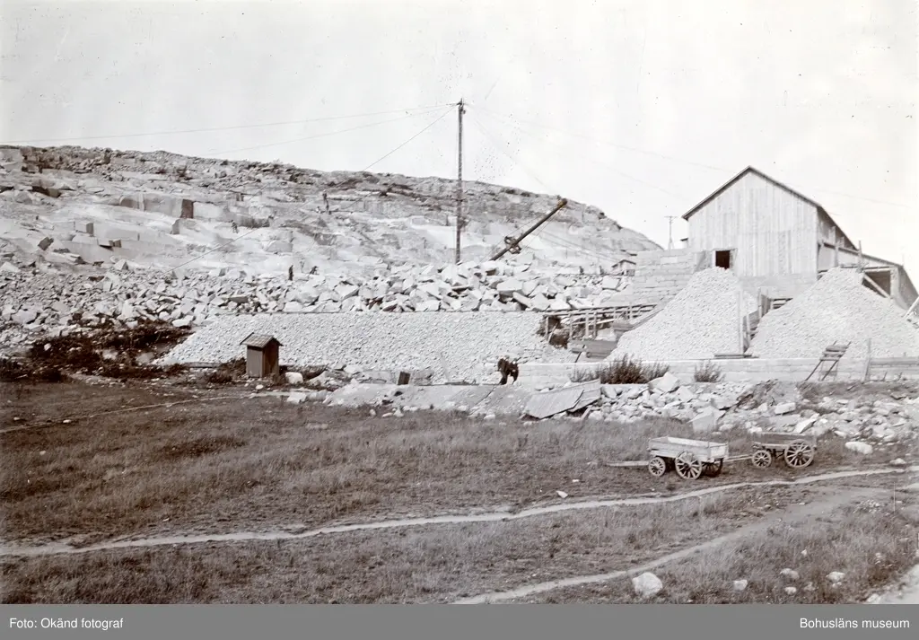 "Rixön stenhuggerier, (exteriör av fabriken för maskinhuggning av smågatsten med upplag av sådan sten, den 29 aug. 1906, Då Tekniska Samfundet i Göteborg besökte Rixön, på inbjudan av Skandinaviska Granit Aktiebolaget, Halmstad."