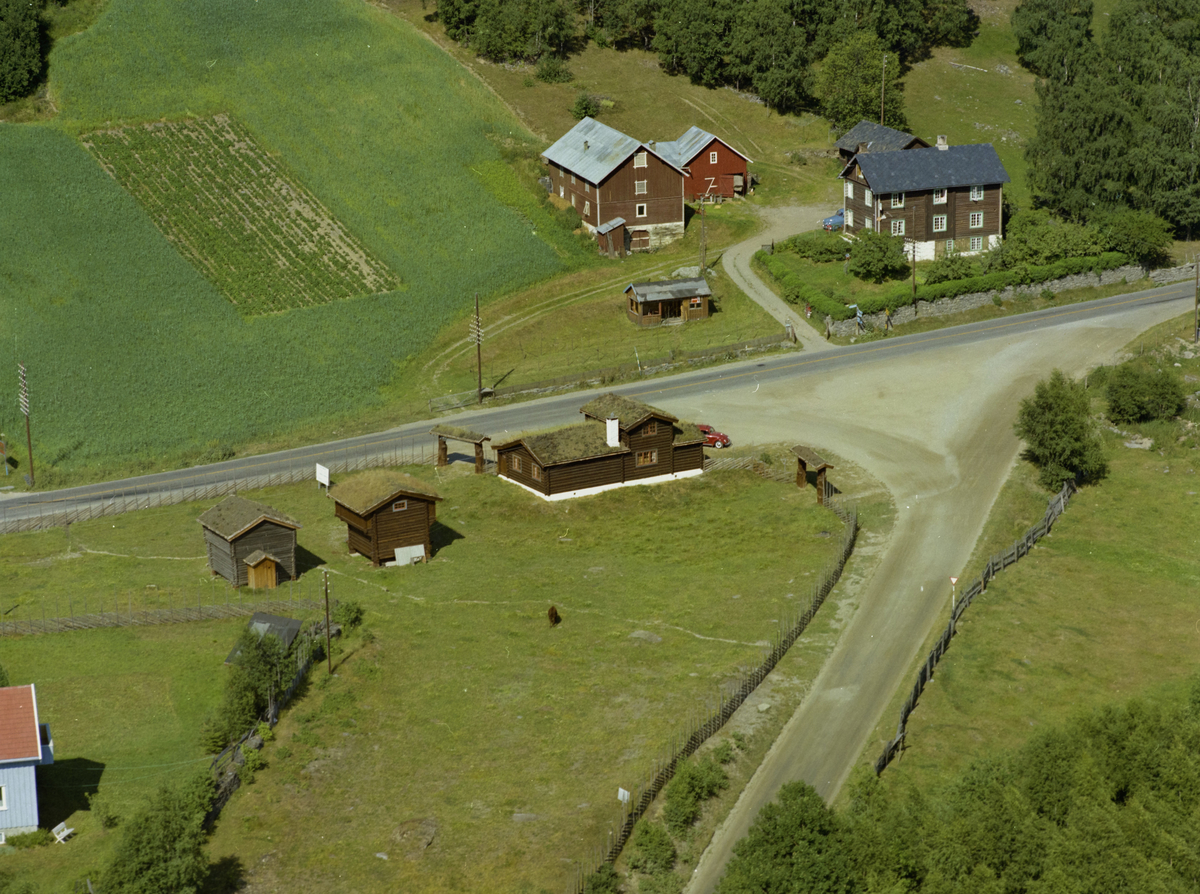 Sør-Fron, Harpefoss. Grøntuva Øvre. Gamle tømmerbygninger, torvtak. Blå bil bak og kjøkkenhage foran. Gålåvegen kommer opp fra nedre billedkant og møter E6 nedenfor gården.