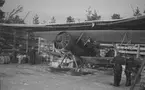 Flygplan Hawker Hart blå R står i värn och lastad med bomber under varmkörning inför start. Vid F 19, Svenska frivilligkåren i Finland, den 23 januari 1940. Militärer i arbete med flygplanet. Åke Mörne och Björn Bjuggren i flygplanet.