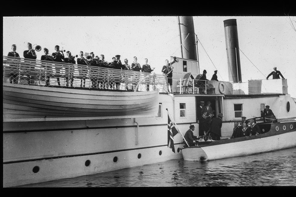 Toftes Gave, Nedre Sund, Helgøya. Gutter går ombord i Kong Oscar,  motorbåt, Nessundet. Guttemusikken på tur til Lillehammer. Musikkorps. Mjøsbåt.