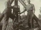 Två män i arbete.
Hjälmsätrakabeln. Vinsch för kabeldragning. Ur albumet Kabelarbetet. Hjälmsälra - Norrtälje - Finnviken utfört under sommaren 1928.