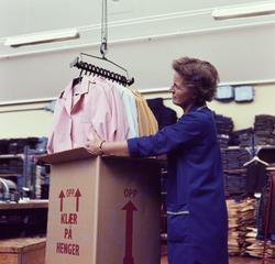 Kvinnelig arbeider pakker klær i esker i ferdiglageret til k