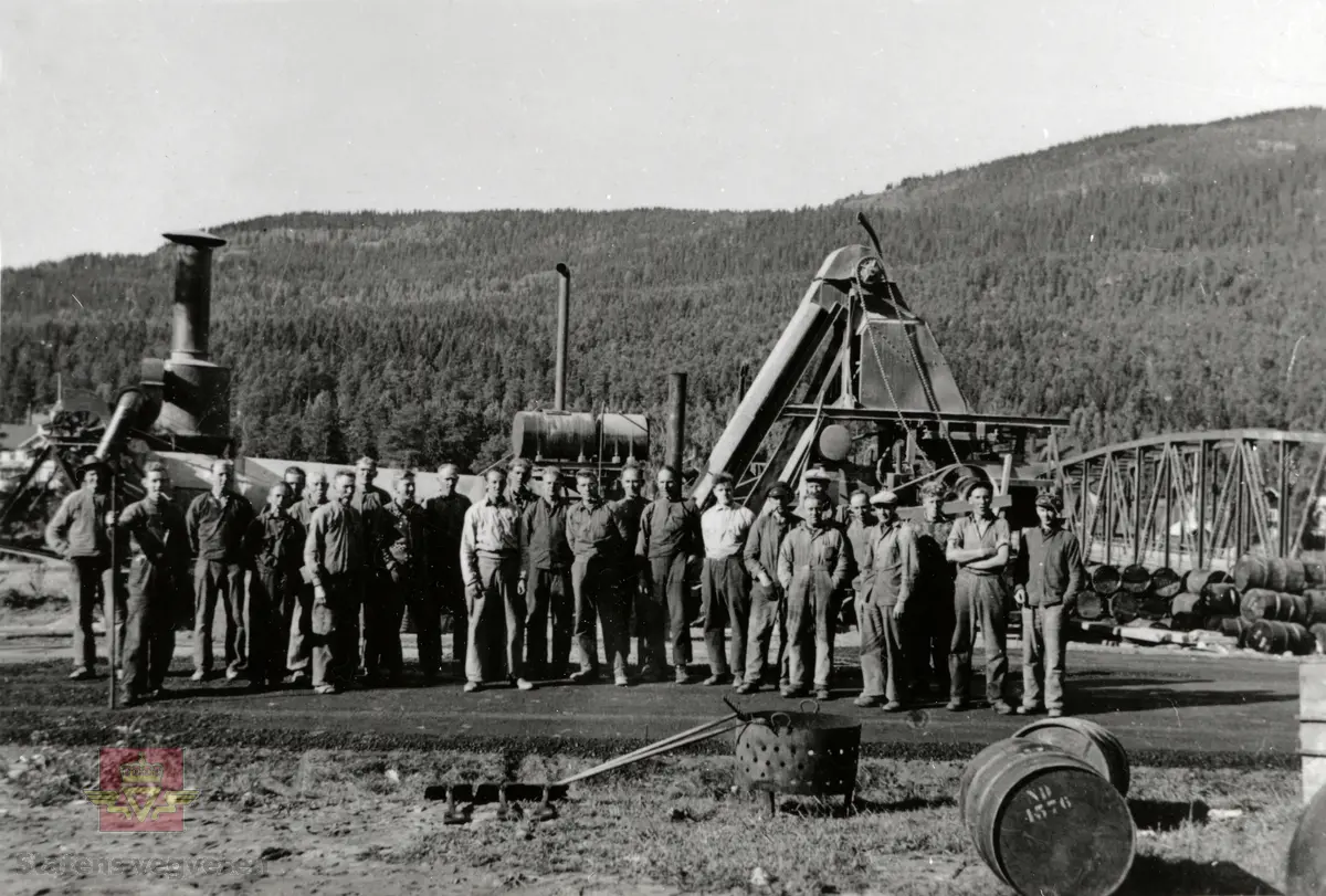 Arbeidslag legger asfalt på Tretten i Gudbrandsdalen. I bakgrunnen skimtes den gamle fagverksbrua fra 1890-tallet. 

08.01.2018: "Det er 25 karer på bildet, de fleste lokale størrelser. Fra venstre nr 1 Kristian Kraabøl Bergmo, 2 Alf Kraabøl, 3 ukjent, 4 Nils Brodal, 5 ukjent, 6 ukjent, 7 Johan M. Kraabøl (vegvokter), 8 Johan Hovdsveen, 9 Magne Kraabøl, 10 Johan Flatemo, 11 Alf Formo, 12 ukjent, 13 ukjent, 14 Wilhelm Olsen, 15 Hans Strangstadstuen, 16 Arnt Løvmo, 17 Reidar Løvmo, 18 ukjent, 19 Karsten Nordgård, (foran Gunnar) 20 Gunnar Flatemo (bakerst), 21 ukjent, 22 ukjent, 23 Ingvald Botheim, 24 ukjent og 25 Alfred Stalsberg". 

Se mer informasjon om dette bildet under Historikk lenger ned på siden. Opplysningene er gitt av Odd Bjerke. 

Klikk på pilen til høyre og se bilde av Tretten og Øyer bru i Øyer kommune i 1895. Bildene er fra amtsingeniør Nikolai Olaf Saxegaards album hvor bruene er avbildet. Se Relasjon og relaterte objekter NVM 00-F-03205 og NVM 00-F-03206 for mer informasjon lenger ned på siden.