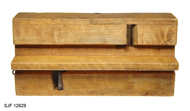 Toveisvirkende høvel for høvling av 2,5-3 centimeter brede flater parallelt med ytterkantene på trematerialer. Høvelstokken er laminert. Kjernen er et 21,9 centimeter lang, 7,1 centimeter høy og 1,0 centimeter tjukt bord av et lyst, hardt treslag.  Den nedre delen av denne komponenten danner styrekant for redskapet. Til begge sideflatene er det pålimt stokker med gjennombrudte sponrom, som er vendt hver sin veg.  Høveltennene er smidd av 2,5 og 3,0 centimeter brede stålplater. De har forholdsvis rettslipte egger. I overendene er det 1,4 og 2,0 centimeter brede ører med gjennombrutte, gjengete hull. I disse hullene er det innskrudd skruer mot "senga" i sponrommenes bakkant. Den ene skruen har vingemutterhode, den andre et sirkelrundt, skiveformet hode. Skruene holder tennene i spenn mellom sponrommets nederkant og ei messingstang som er inntappet på tvers av høvelstokken, gjennom den øvre delen av sponrommene.  Ytterflatene på høvelen har ei gulbrun fargetone, antakelig etter oljing.  På høvelstokkens venstre sideflate er det en innskrift: "Micel, 1903".  I fronten av stokken er det innslått ei galvanisert jernkrampe (en king), antakelig fordi redskapet har vært opphengt som dekorasjon etter at det ble slutt med å bruke det som arbeidsredskap.