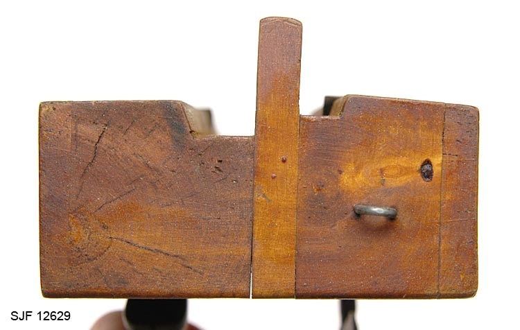 Toveisvirkende høvel for høvling av 2,5-3 centimeter brede flater parallelt med ytterkantene på trematerialer. Høvelstokken er laminert. Kjernen er et 21,9 centimeter lang, 7,1 centimeter høy og 1,0 centimeter tjukt bord av et lyst, hardt treslag.  Den nedre delen av denne komponenten danner styrekant for redskapet. Til begge sideflatene er det pålimt stokker med gjennombrudte sponrom, som er vendt hver sin veg.  Høveltennene er smidd av 2,5 og 3,0 centimeter brede stålplater. De har forholdsvis rettslipte egger. I overendene er det 1,4 og 2,0 centimeter brede ører med gjennombrutte, gjengete hull. I disse hullene er det innskrudd skruer mot "senga" i sponrommenes bakkant. Den ene skruen har vingemutterhode, den andre et sirkelrundt, skiveformet hode. Skruene holder tennene i spenn mellom sponrommets nederkant og ei messingstang som er inntappet på tvers av høvelstokken, gjennom den øvre delen av sponrommene.  Ytterflatene på høvelen har ei gulbrun fargetone, antakelig etter oljing.  På høvelstokkens venstre sideflate er det en innskrift: "Micel, 1903".  I fronten av stokken er det innslått ei galvanisert jernkrampe (en king), antakelig fordi redskapet har vært opphengt som dekorasjon etter at det ble slutt med å bruke det som arbeidsredskap.
