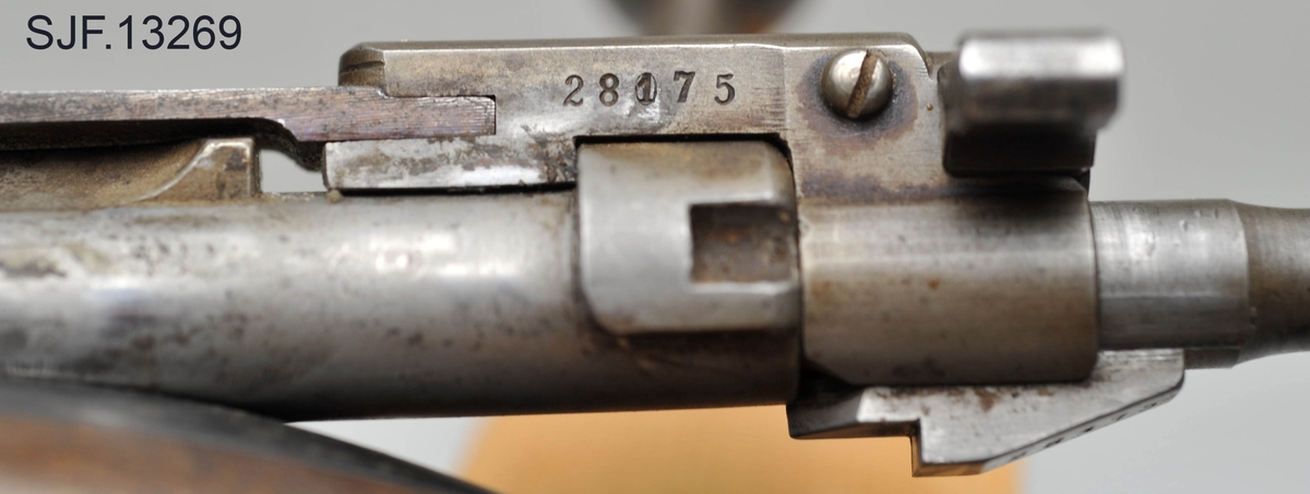 Krag-Jørgensen rifle med kaliber 6, 5 x 55. Geværet har pistolgrep. Magasinkapasitet på 5 patroner. Kolben er brunbeiset / oljet. Kolbekappe av stål. På munningen er det festet ei messinghette, en snø- og vannbeskytter. Geværet er utstyrt med høydejusterbart skur og sidejusterbart korn. 
Det er bærereim påmontert geværet. 