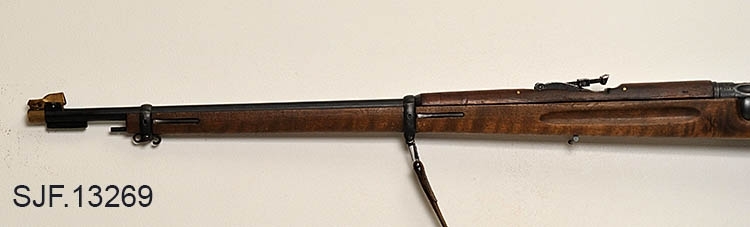 Krag-Jørgensen rifle med kaliber 6, 5 x 55. Geværet har pistolgrep. Magasinkapasitet på 5 patroner. Kolben er brunbeiset / oljet. Kolbekappe av stål. På munningen er det festet ei messinghette, en snø- og vannbeskytter. Geværet er utstyrt med høydejusterbart skur og sidejusterbart korn. 
Det er bærereim påmontert geværet. 