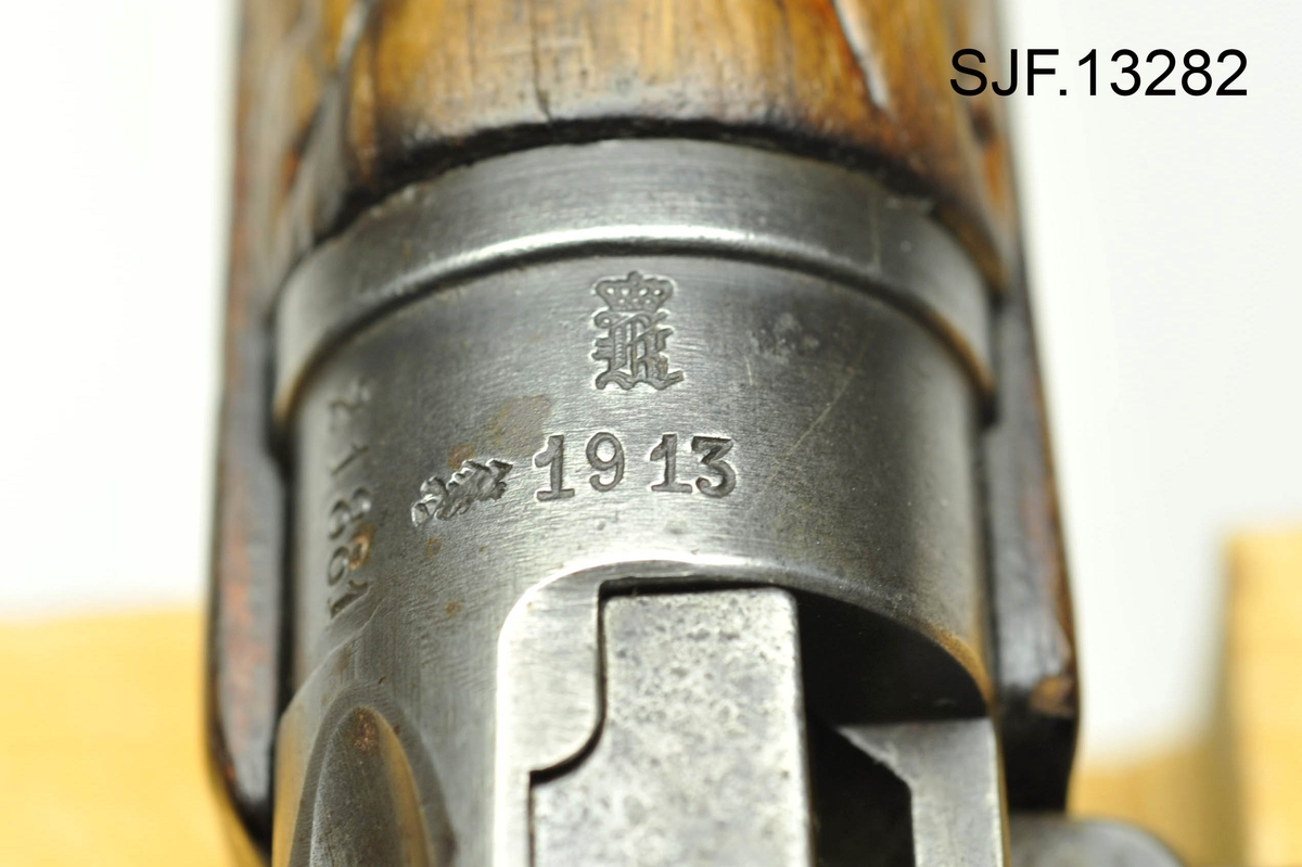 Krag-Jørgensen rifle med kaliber 6, 5 x 55. Geværet har pistolgrep. Magasinkapasitet på 5 patroner. Kolben er brunbeiset / oljet. Skjeftet er dekorert med forseggjorte utskjæringer.  Kolbekappen av stål har innfelt et lokk. Om man åpner lokkket kommer man til et "oppbevaringsrom" i kolben. Treverket som omslutter undersiden av geværløpet har noen sprekkdannelser.  Geværet er utstyrt med høydejusterbart skur og sidejusterbart korn. 
